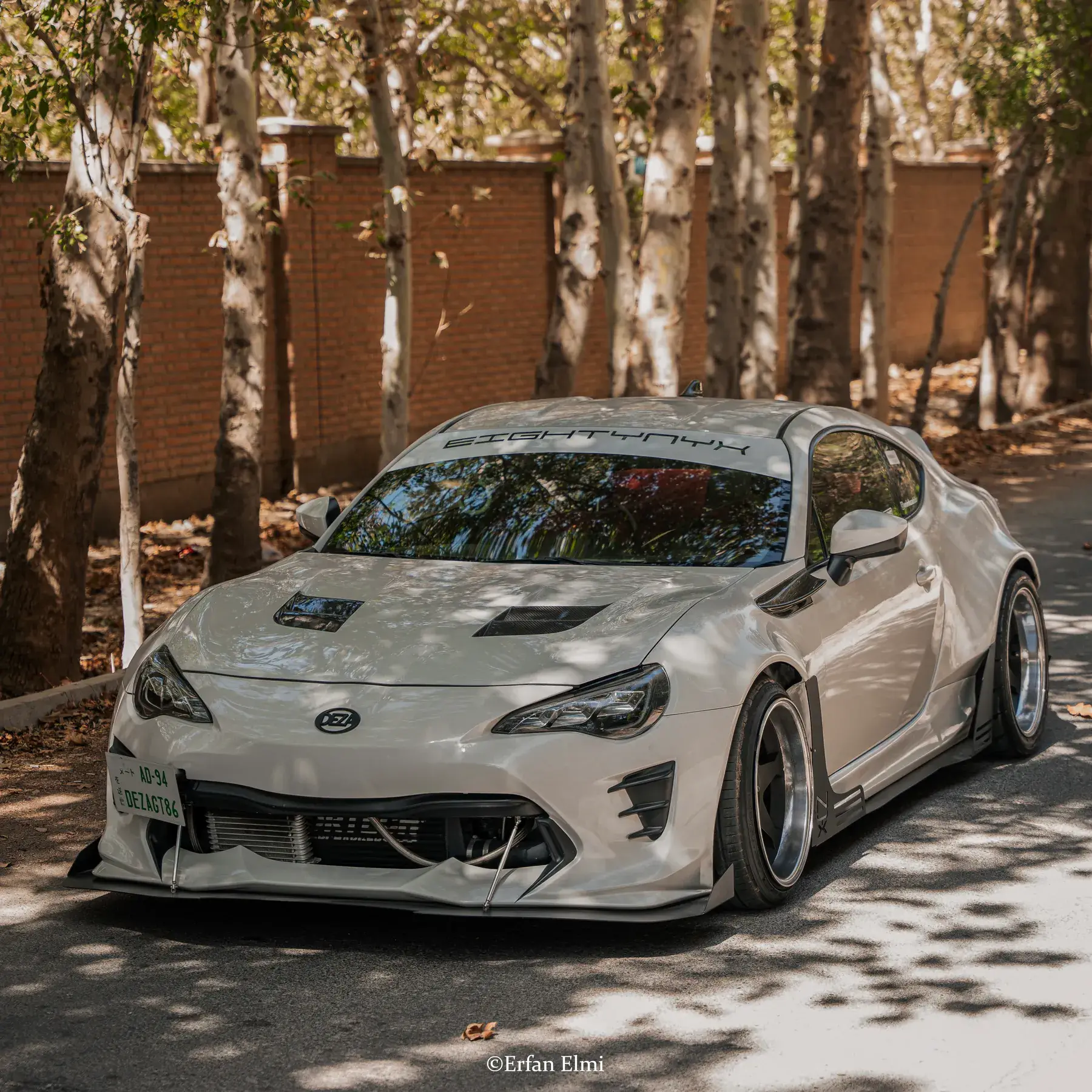 NYX, a white widebody Toyota GT86, parked under trees