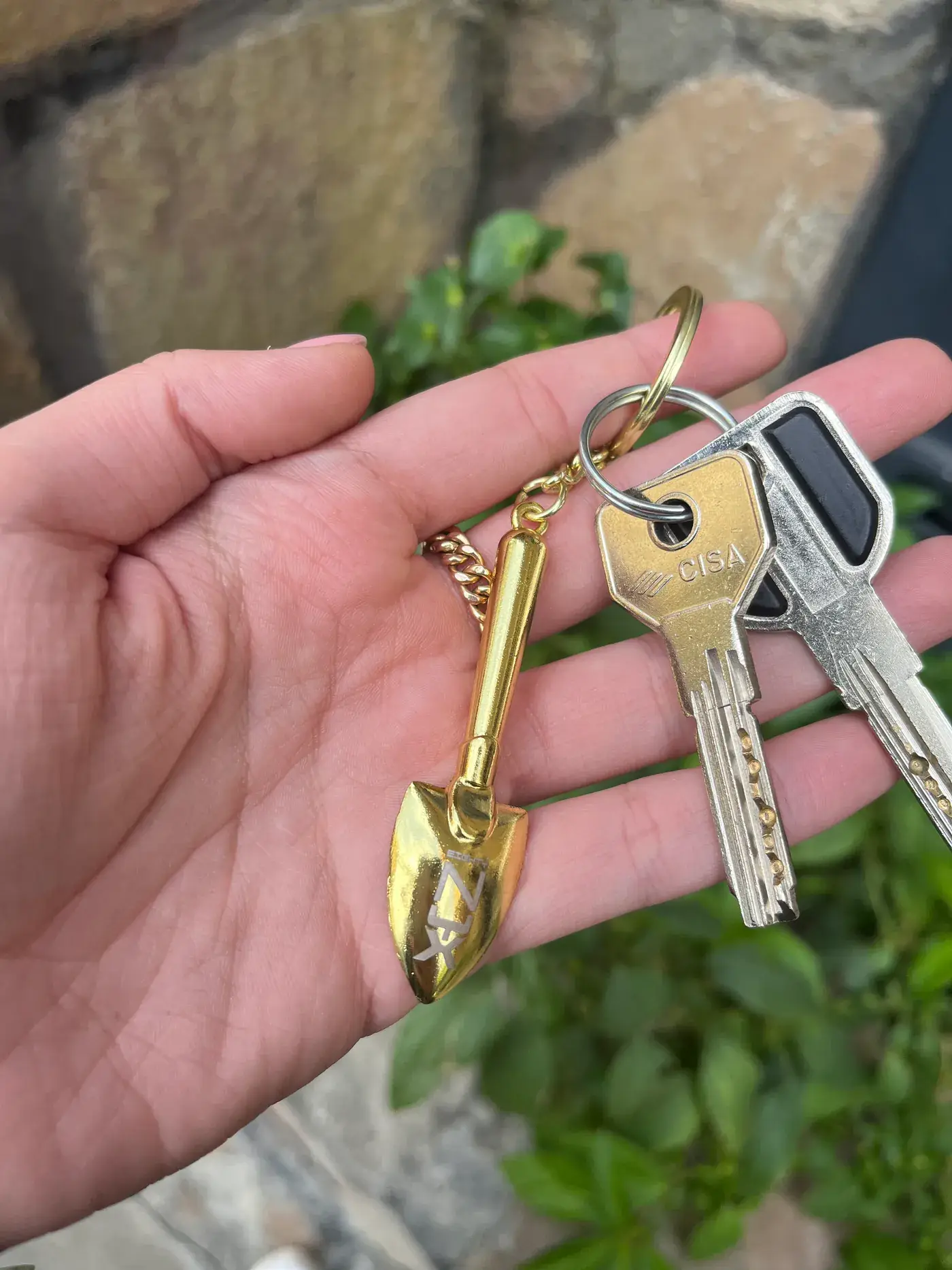 Gold shovel keychain held in hand
